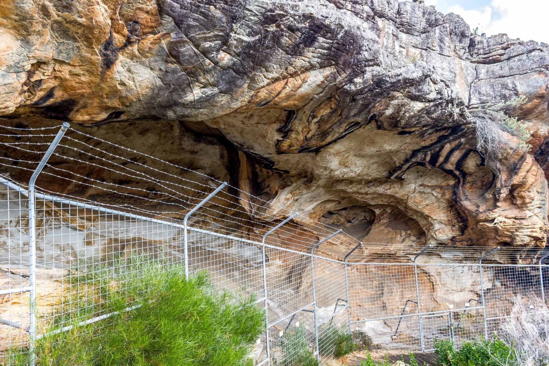 View the painted hands behind a rock-art shelter's fence